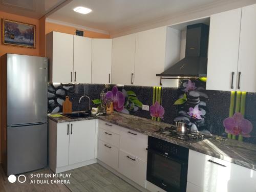 a kitchen with white cabinets and a stainless steel refrigerator at Современная квартира с видом на горы in Almaty