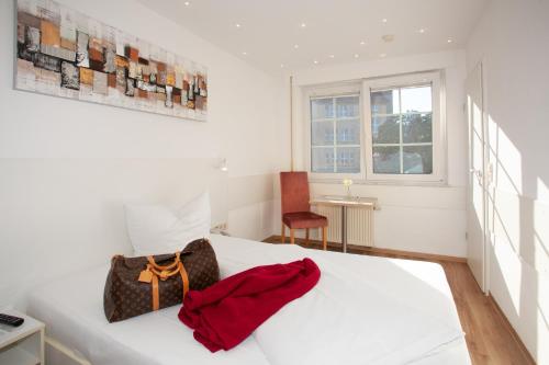 a bedroom with a white bed with a red bag on it at Relax Hotel & SPA Stuttgart in Stuttgart