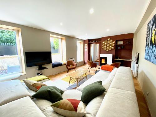 a living room with a white couch and a tv at Le Capella, magnifique maison au calme avec garage in Caen