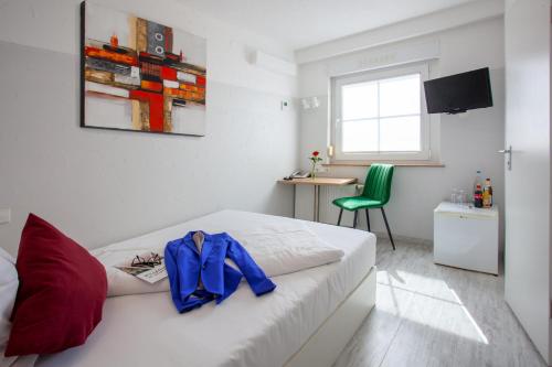 a bedroom with a white bed and a green chair at Relax Hotel & SPA Stuttgart in Stuttgart