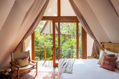 a bedroom with a bed and a large window at Our Habitas Bacalar in Bacalar