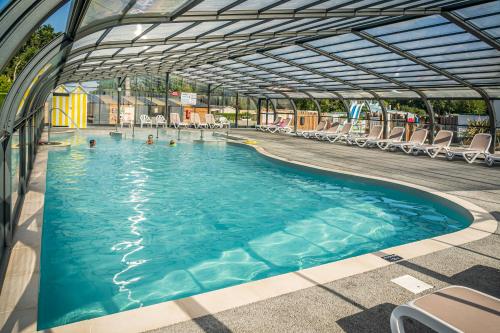 une piscine avec des chaises et des gens dans l'eau dans l'établissement Camping Ker Yaoulet - Maeva, à Ambon