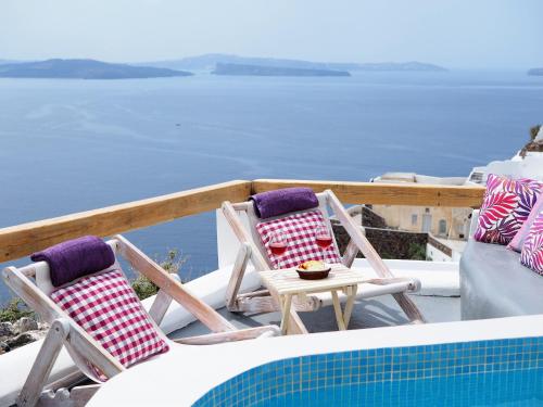 two chairs and a table next to a swimming pool at Aqua & Terra Traditional Cave Houses in Oia