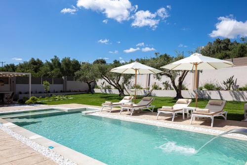 una piscina con sedie e ombrelloni in un cortile di Koin Villa Sunrise, with Heated Pool & Whirlpool a Perama