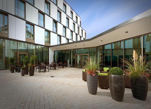 a courtyard with potted plants in front of a building at Vienna House Easy by Wyndham Osnabrück City & Apartments in Osnabrück