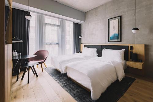 a hotel room with two beds and a table and a desk at Nobu Hotel Warsaw in Warsaw