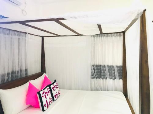 a bedroom with a bed with pink and white pillows at Jilan Homestay in Bentota