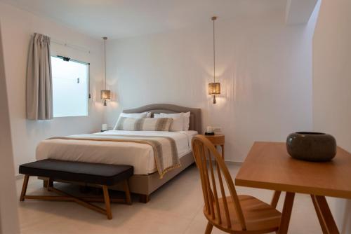 een slaapkamer met een bed, een tafel en een stoel bij La Maltese Residence in Imerovígli