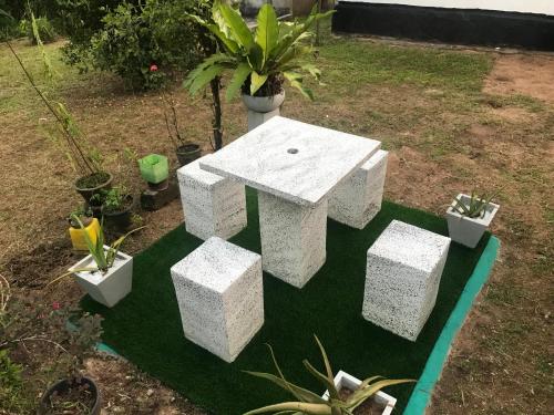 a concrete picnic table in a garden with potted plants at Jilan Homestay in Bentota
