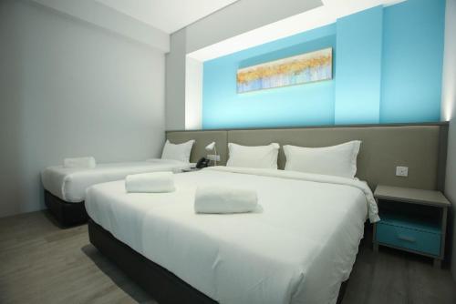 a hotel room with two beds with white sheets at Stanton City Hotel in Kota Kinabalu