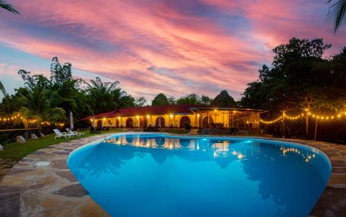a swimming pool in front of a building with a sunset at Apu Samay Nature Lodge in Tarapoto