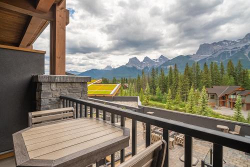 a wooden bench on a balcony with a view of mountains at The Malcolm Hotel in Canmore