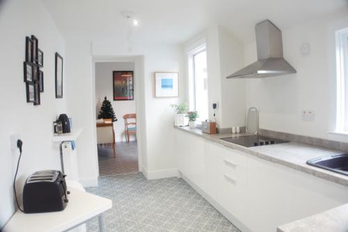 a white kitchen with a sink and a counter at Barns Serviced Accommodation in Ayr