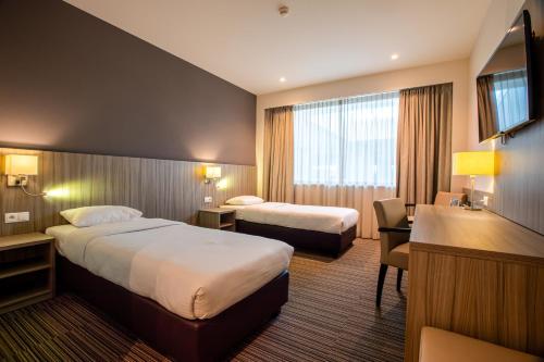 a hotel room with two beds and a desk at Mezzo Hotel & Business in Beringen