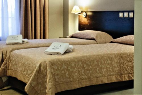 two beds in a hotel room with towels on them at Grand Hotel Dentro in Konitsa
