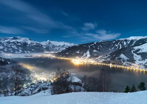 a view of a city in the snow at night at Familotel Amiamo in Zell am See
