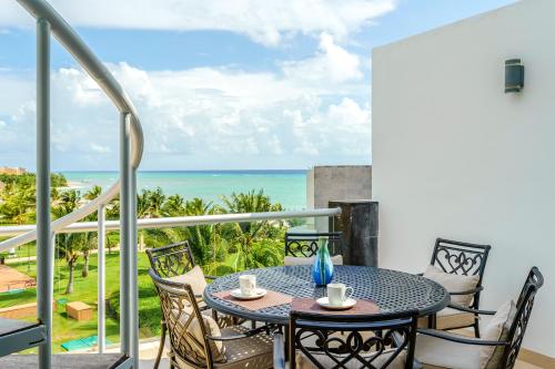 a table on a balcony with a view of the ocean at Luxury Condos at Mareazul Beachfront Complex with Resort-Style Amenities in Playa del Carmen