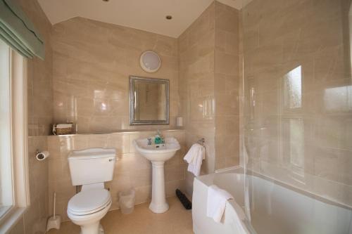 a white toilet sitting next to a bath tub in a bathroom at Hotel Rudyard in Leek