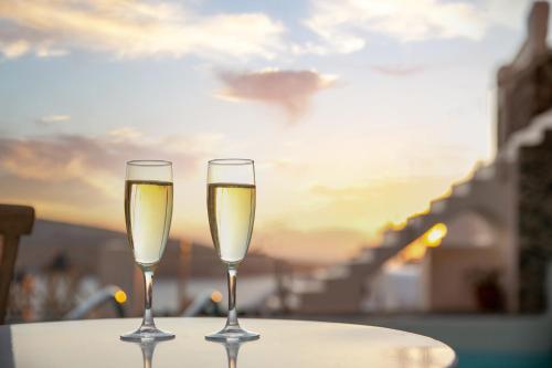 two glasses of white wine sitting on a table at Oia Mare Villas in Oia