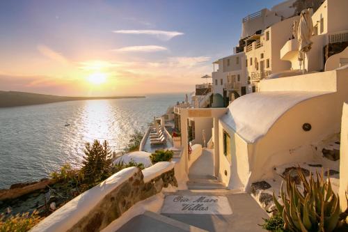 a sunset over the ocean on the side of a building at Oia Mare Villas in Oia