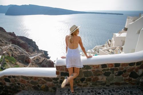 a woman standing on a ledge looking out at the water at Oia Mare Villas in Oia