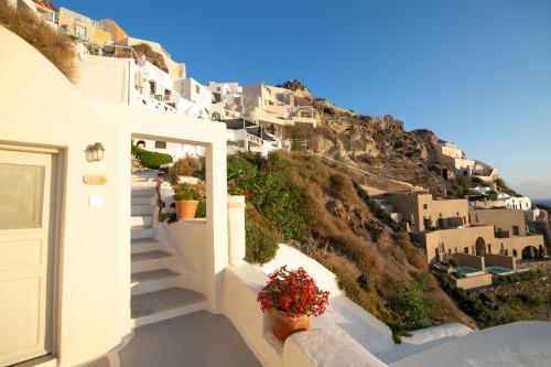 a view of a mountain with white houses and flowers at Oia Mare Villas in Oia