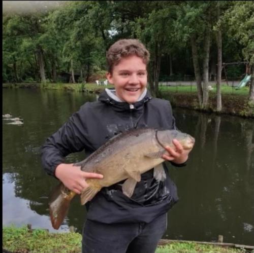 a boy holding a fish in front of a pond at LE CHALET DE CANDICE TOUT CONFORT PECHE COMPRISE in Saint-Michel