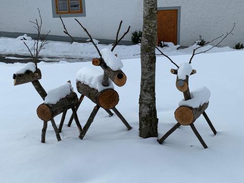 a group of sculptures in the snow next to a tree at Ferienwohnung-Mühlviertel in Oepping