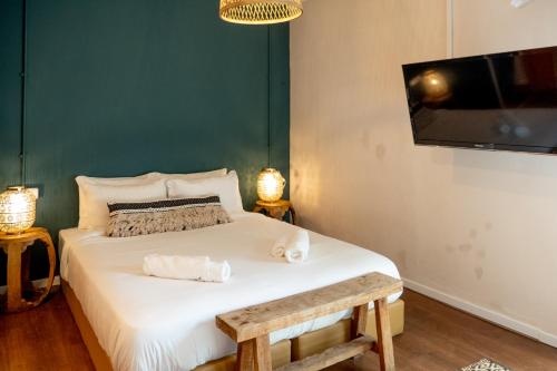 a bedroom with a bed with a tv and a bench at Beit Oren Hotel in Bet Oren