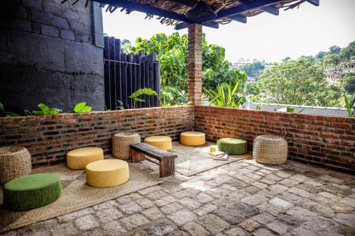 een patio met krukken, een bank en een bakstenen muur bij Banana Bunks Kandy in Kandy