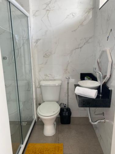 a white bathroom with a toilet and a sink at Casa de Praia - Suítes in Arraial do Cabo