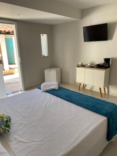 a large bed in a room with a tv on the wall at Casa de Praia - Suítes in Arraial do Cabo