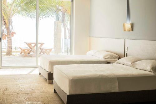 3 Betten in einem Zimmer mit einem großen Fenster in der Unterkunft Hotel Casa Danae in Tolú