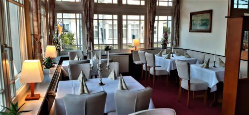 a restaurant with white tables and chairs and windows at Hotel Meereswelle - Anno 1875 in Ahlbeck