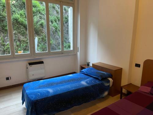 a bedroom with a blue bed and two windows at Appartamenti Lago di Como in Valbrona