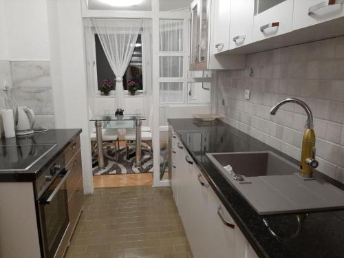 a kitchen with a sink and a table in it at Apartman Hana in Sanski most