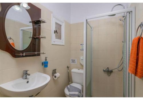 Un baño con lavabo, inodoro y ducha. en Avgerinos Deluxe Rooms, en Paliochori