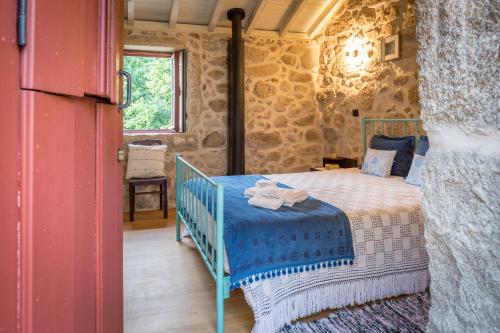 a bedroom with a bed in a stone wall at Traços D'Outrora in Vale de Cambra