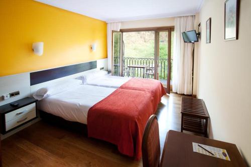 a hotel room with a large bed and a balcony at Hotel Venta de Etxalar in Etxalar