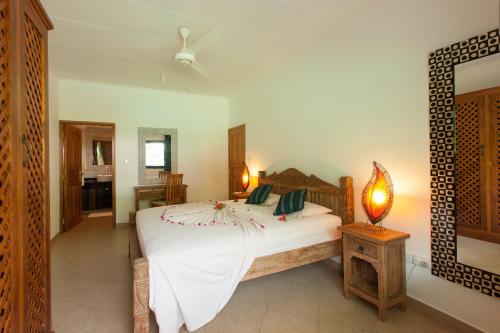 a bedroom with a bed with white sheets and a ceiling fan at Villa Face Mer in Anse Volbert Village