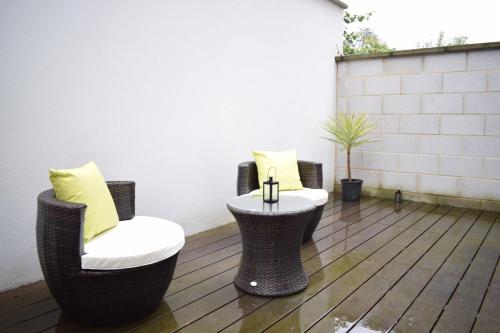 a patio with two chairs and a table with yellow pillows at Beautiful Modern 1 Bedroom Apartment in North London in London