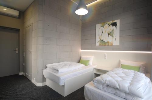 two beds in a room with white walls at Cubby Hotel in Lviv
