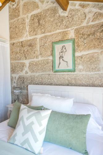 a bedroom with a stone wall and a white bed at Casa Monte do Cervo in Vila Nova de Cerveira