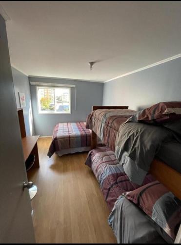a room with three beds and a window at Apart Hotel Temuco in Temuco