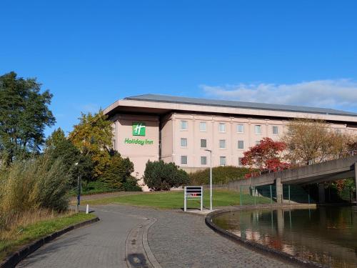 un grand bâtiment à côté d'une rivière avec un pont dans l'établissement Holiday Inn Gent Expo, an IHG Hotel, à Gand