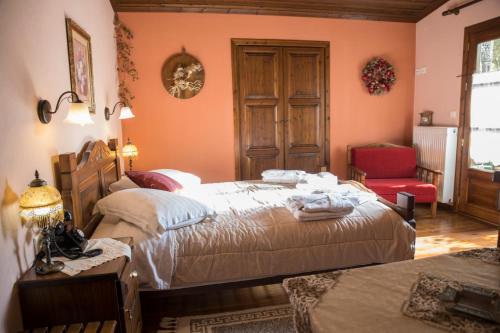 a bedroom with two beds and a red chair at Archontiko Tsiboni in Elati Trikalon