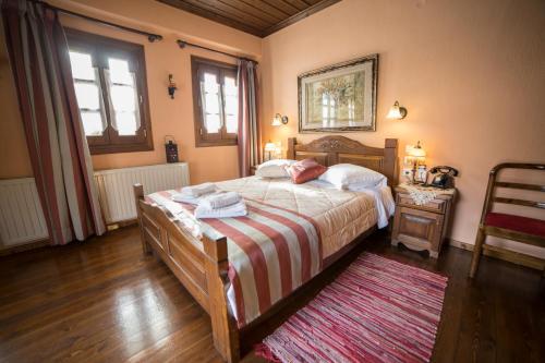 a bedroom with a large bed with a striped blanket at Archontiko Tsiboni in Elati Trikalon