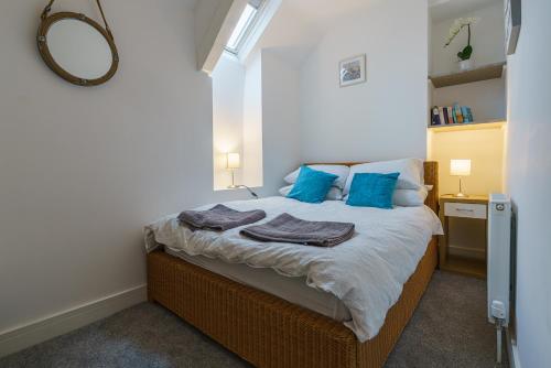 a bedroom with a bed with blue pillows and a mirror at Private deck with newly refurbished flat attached! in Cirencester