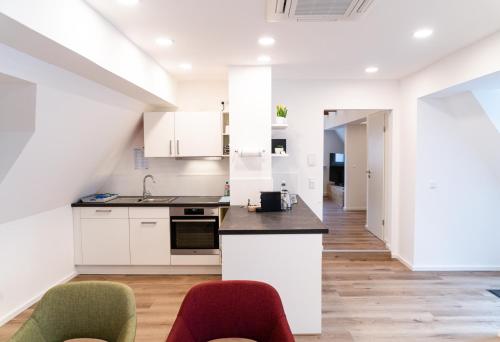 una cocina abierta con armarios blancos y 2 sillas en AMBERG [APART] - Wohnung [CITY] - Wohnraum auf Zeit, en Amberg