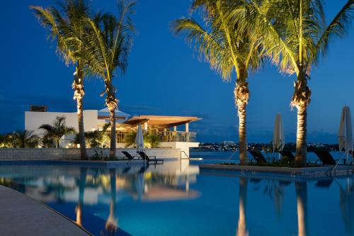 a pool with palm trees in front of a building at Hamilton Princess & Beach Club A Fairmont Managed Hotel in Hamilton